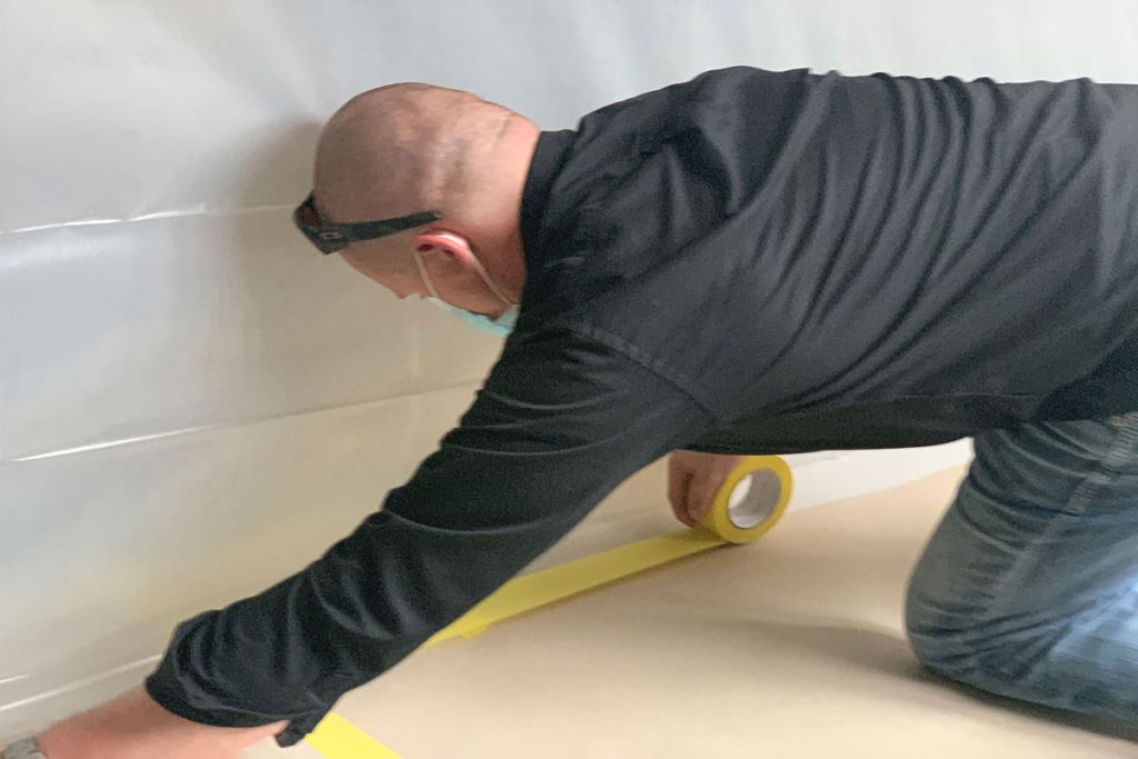 Worker taping down plastic containment