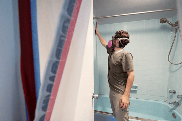 Man Wearing Respirator Inspects Home Construction Site after Bathroom Mold Remediation